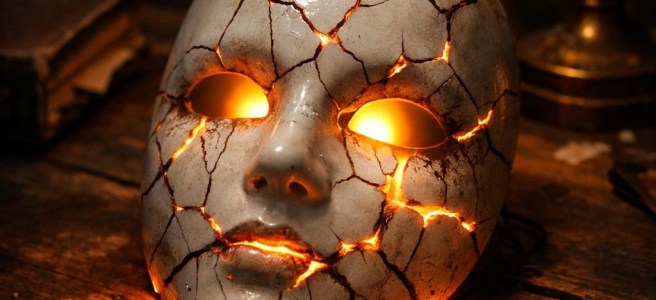 Cracked ceramic mask with glowing light shining through cracks
