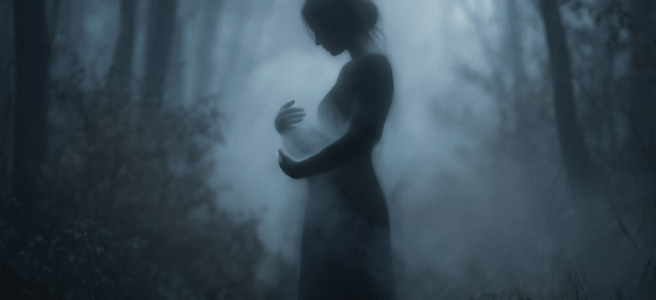 Silhouette of a woman standing in a misty forest, holding her hands near her chest