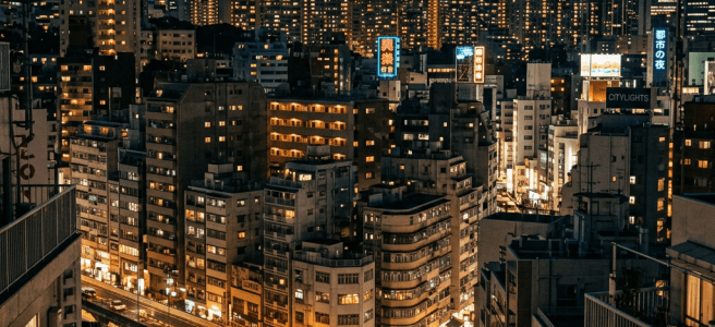 City skyline at dusk with illuminated buildings and traffic on roads
