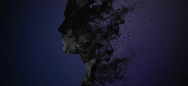 Silhouette of a human head dissolving into black smoky particles on a dark background